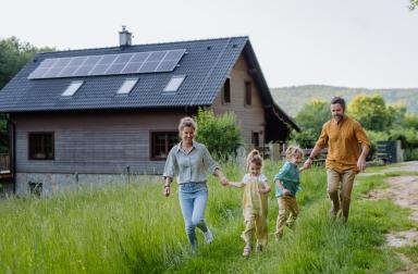 Family walking in the garden in front of their house with solar panels