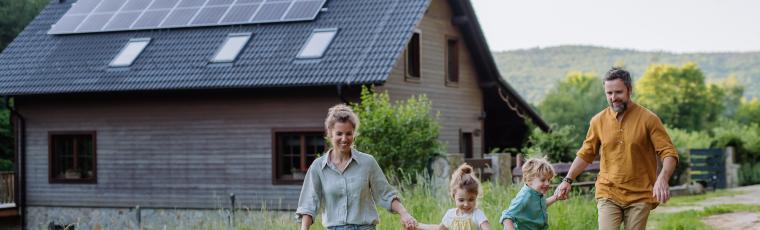 Family walking in the garden in front of their house with solar panels