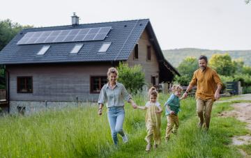 Family walking in the garden in front of their house with solar panels