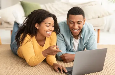 Couple regardant les prix de l'énergie sur un ordinateur portable avec le sourire