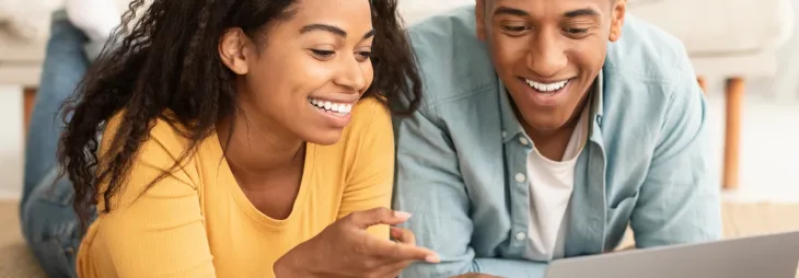 Couple regardant les prix de l'énergie sur un ordinateur portable avec le sourire