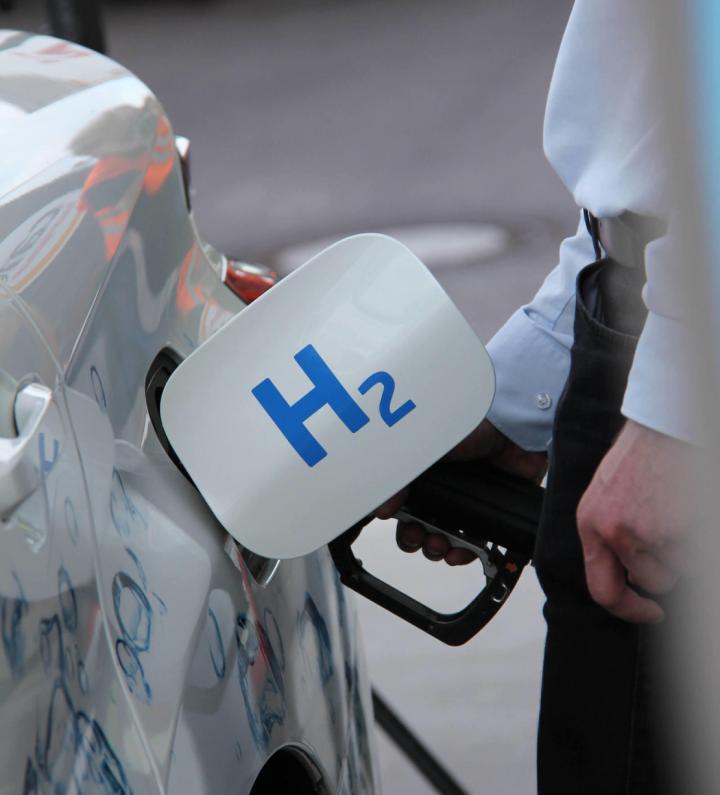Someone putting hydrogen in their car at a gas station