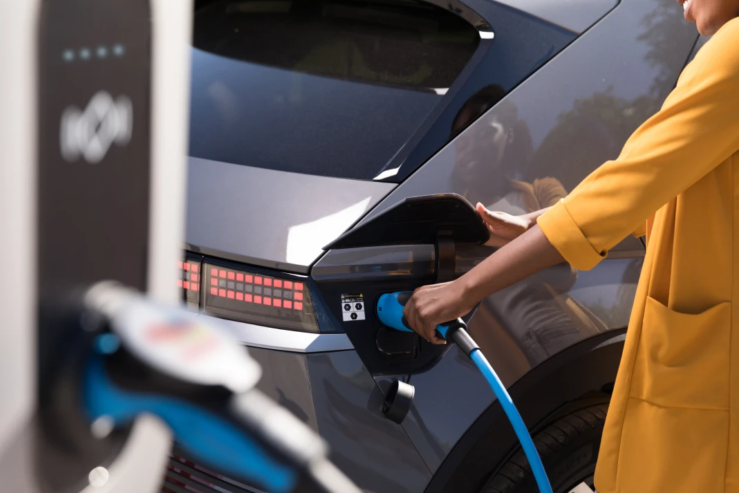 Femme rechargeant son véhicule électrique à une borne de recharge