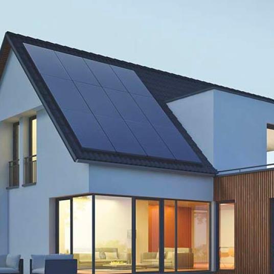 House with photovoltaic pannels on the roof, lit up inside