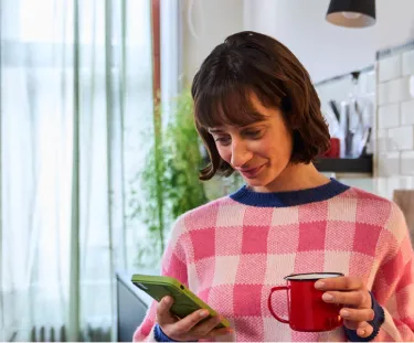 Woman checking her energy consumption on her mobile phone in the kitchen
