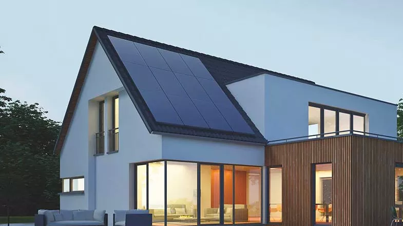 House with photovoltaic pannels on the roof, lit up inside